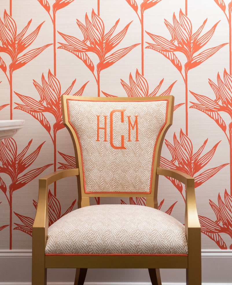 Statement gold arm chair with flared back. Personalized with a coral monogram in block letters on a tan and white patterned fabric with coral welt.